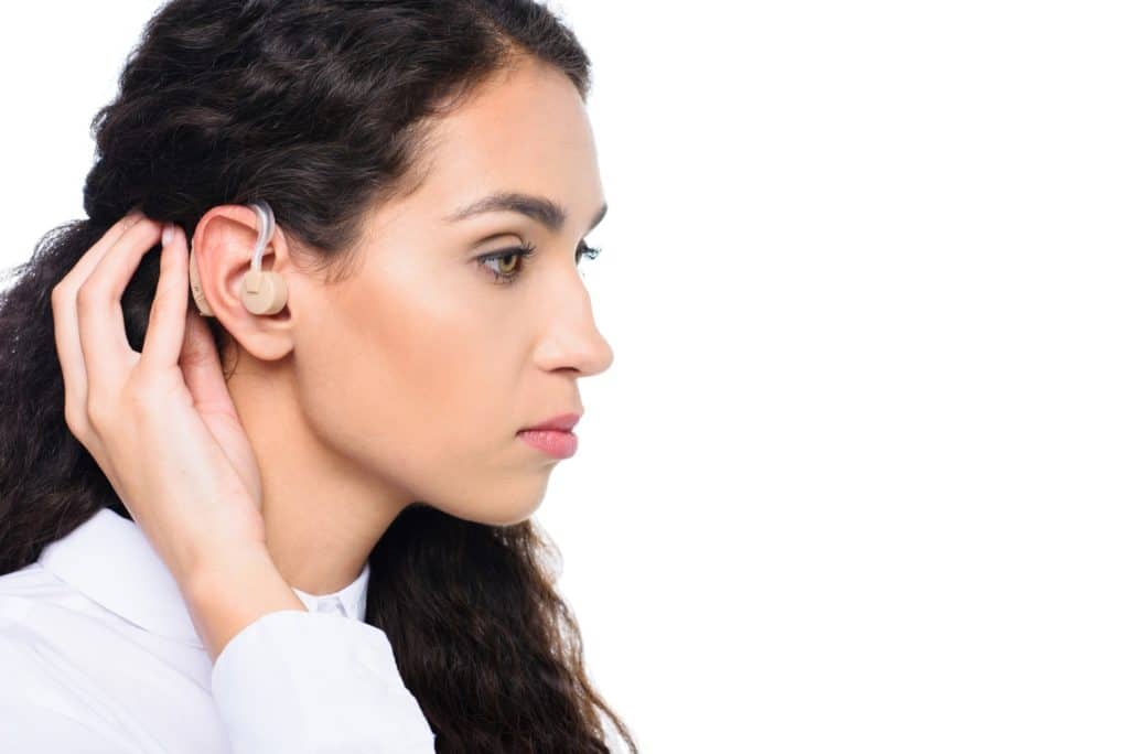 attractive brunette woman with hearing aid, isolated on white